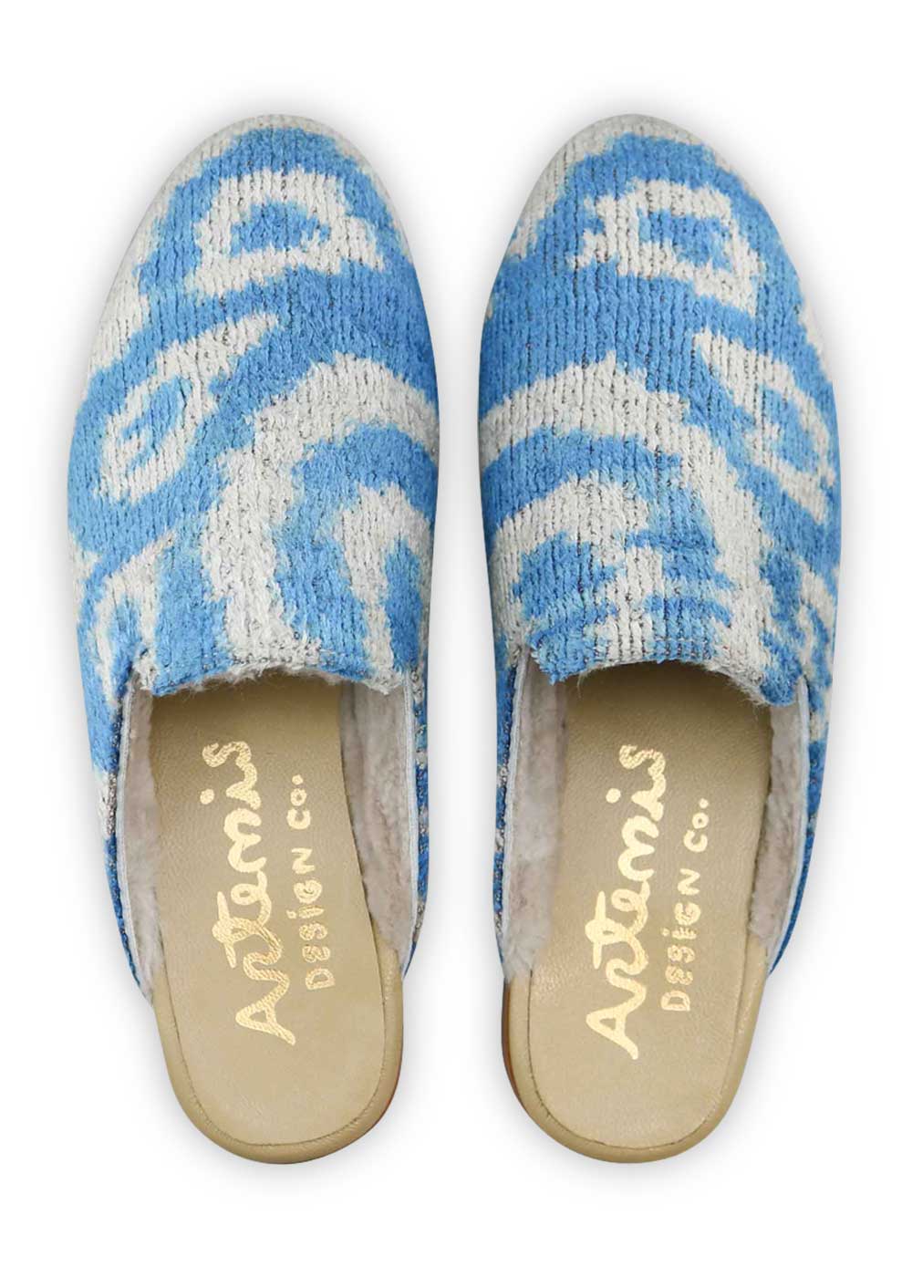 Artemis Design Co Women's Shearling-Lined Velvet Slippers in a chic color combination of white and powder blue offer a luxurious and stylish footwear option. Crafted with attention to detail, these slippers feature a plush shearling lining for warmth and comfort. The velvet exterior exudes elegance, and the white and powder blue color palette adds a touch of sophistication. (Front View)