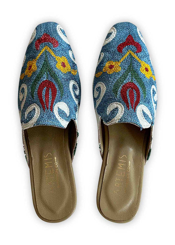  Introducing Artemis Design Co Women's Mules, where classic elegance meets playful charm in a delightful color combination of white, blue, yellow, and green. These meticulously crafted mules effortlessly blend vibrant hues for a refreshing yet refined look. Whether you're stepping out for brunch or attending a garden party, these mules elevate your ensemble with their timeless style and contemporary design. (Front View)