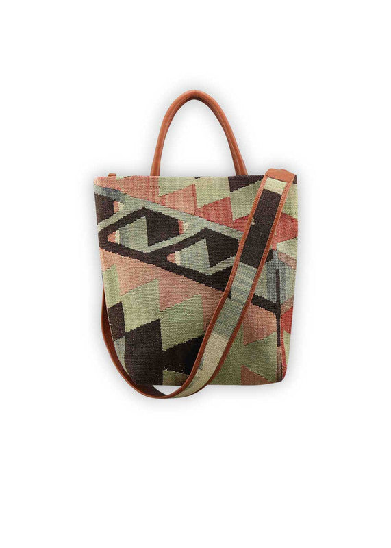 The Artemis Design Co. Sumak Kilim Tote boasts a captivating fusion of tradition and modernity. Crafted with a chic black base, this tote features a vibrant Sumak Kilim pattern adorned with bold accents of red, alongside hues of black, blue, green, and white. The dynamic color palette infuses a contemporary edge into the timeless design, making it a standout accessory for any occasion. (Front View)