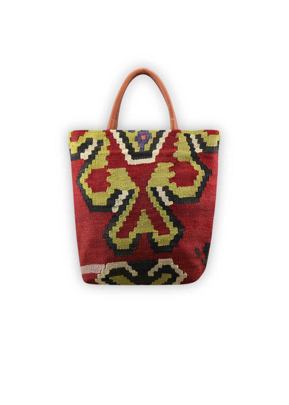 The Artemis Design Co. Sumak Kilim Tote is a striking blend of traditional craftsmanship and contemporary style. Made with premium brown leather accents, this tote features a vibrant Sumak Kilim pattern in a rich array of colors, including apple green, black, red, white, and blue. The harmonious combination of these hues creates a bold and dynamic look, perfect for adding a pop of personality to any ensemble. (Front View)