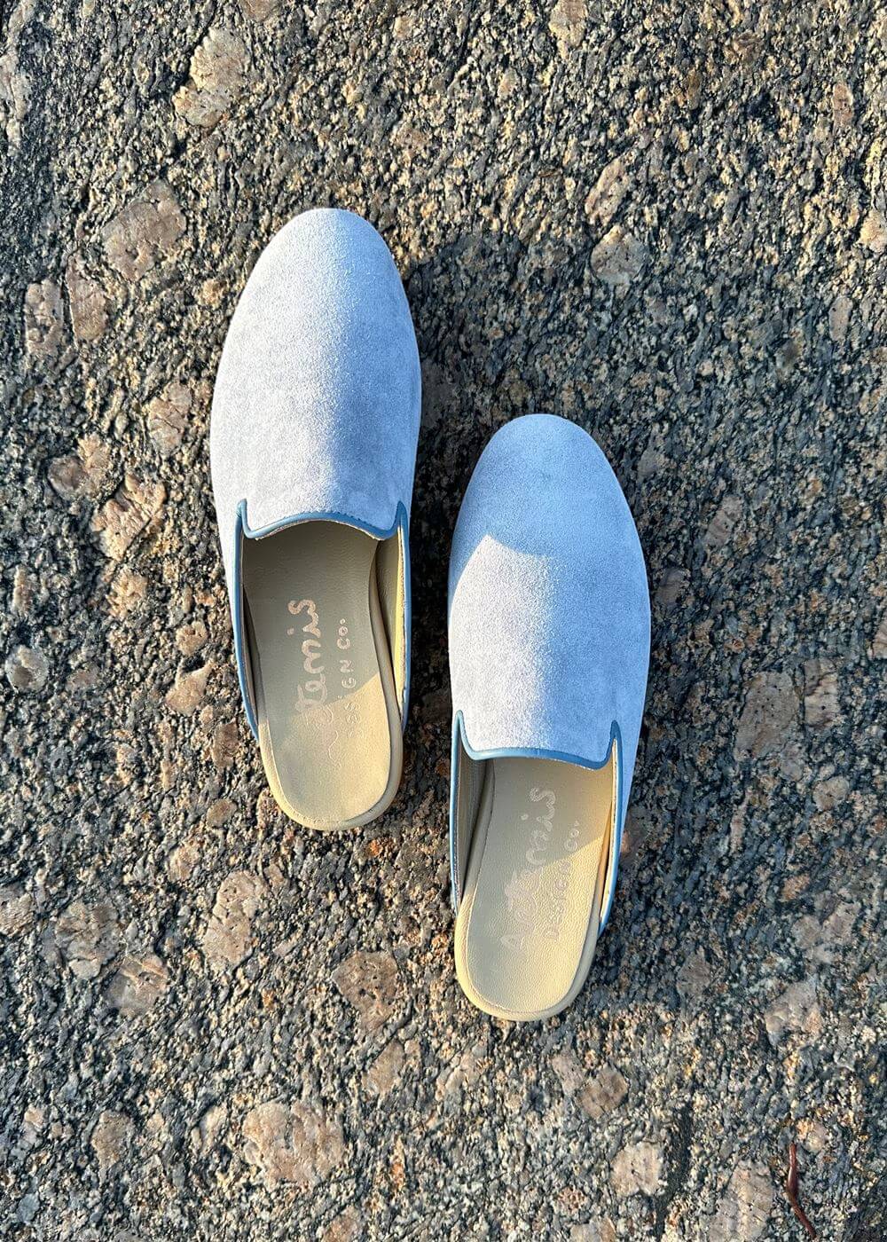 the Suede Slippers in blue from Artemis Design & Co are a must-have for those seeking both comfort and style. Crafted with high-quality suede, these slippers offer a plush and cozy feel for your feet. (Front View)