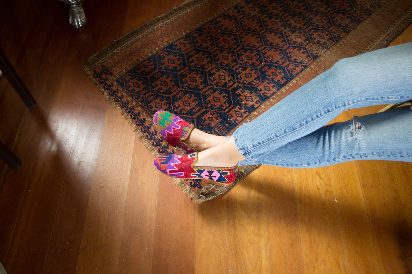 Women's feet resting on the ground wearing women's kilim smoking shoes