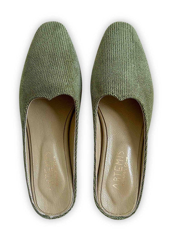 Introducing Artemis Design Co Women's Mules in a captivating shade of green. These stylish mules effortlessly fuse elegance with comfort, making them the perfect choice for any occasion. Crafted with meticulous attention to detail, they boast a timeless design that complements a variety of outfits. Step into sophistication and elevate your ensemble with Artemis Design Co Women's Mules in this refreshing green hue. (Front View)