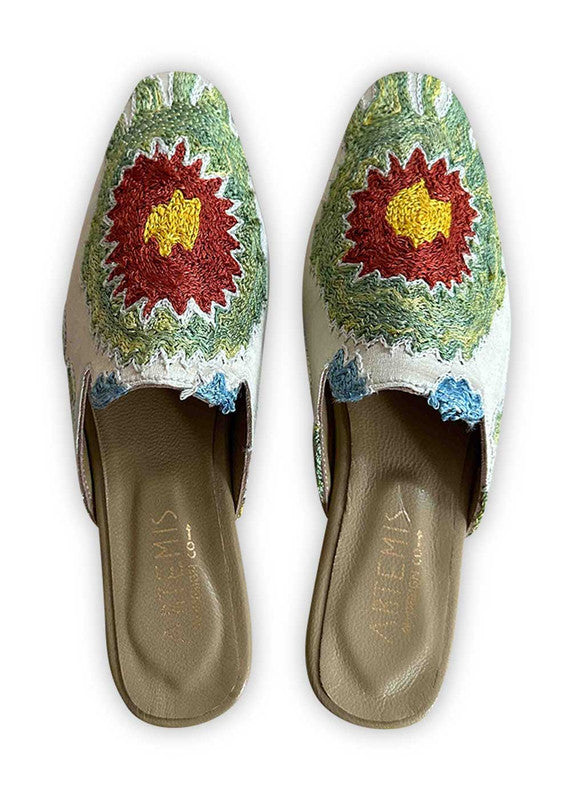 Experience vibrant sophistication with Artemis Design Co Women's Mules featuring a dynamic color combination of white, green, red, yellow, and blue. These meticulously crafted mules effortlessly blend bold hues for a striking yet refined look. Whether you're stepping out for a casual outing or a special occasion, these mules offer both style and comfort. (Front View)