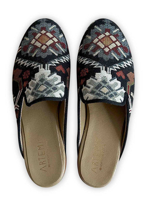 Artemis Design Co's Women's Slippers boast a vibrant color combination of black, red, white, maroon, grey, and blue, offering a stylish and eye-catching footwear option. Crafted with meticulous attention to detail, these slippers feature a plush interior for luxurious comfort and a sleek exterior adorned with a captivating pattern that seamlessly blends the bold hues. (Front View)