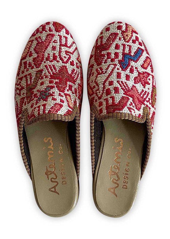 Artemis Design Co's Women's Slippers boast an enchanting color palette of red, white, peach, and grey, creating a harmonious blend of style and comfort. Crafted with meticulous attention to detail, these slippers feature a plush interior for cozy warmth and a sleek exterior adorned with a captivating pattern that seamlessly incorporates the vibrant hues. (Front View)