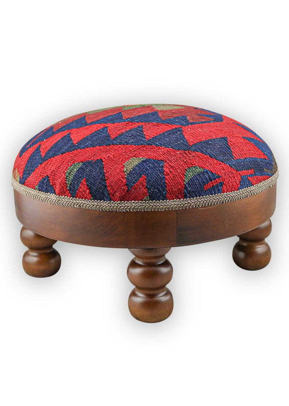  The Artemis Design & Co Footstool is a chic and vibrant accent piece, showcasing a captivating color palette of blue, red, maroon, and grey. Meticulously crafted, this footstool seamlessly blends bold and rich tones, creating a stylish and eye-catching addition to your living space. (Side View)