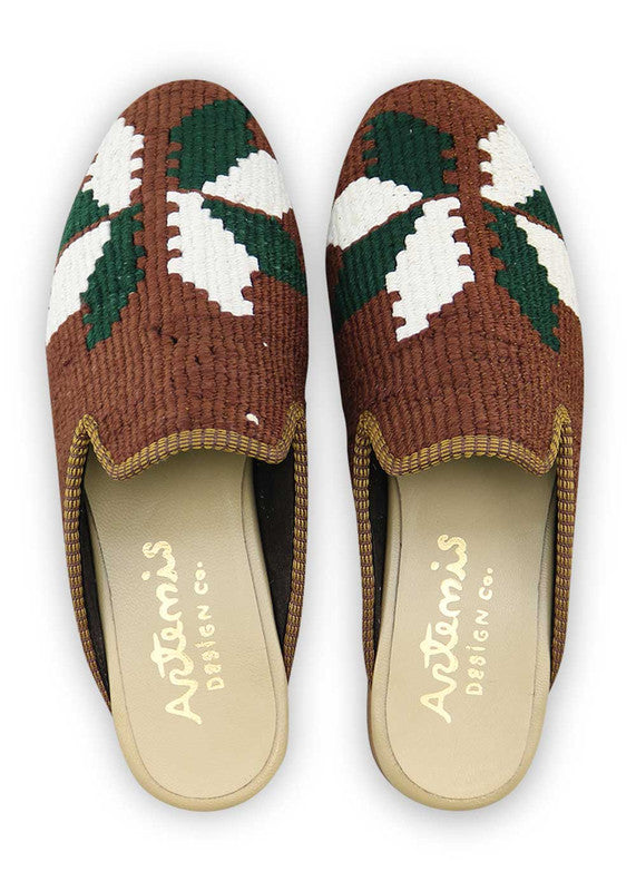 Artemis Design & Co presents Men's Slippers in a refined color palette of brown, white, green, and black. Elevate your relaxation experience with these meticulously crafted slippers that seamlessly blend comfort and style. The earthy tones and monochromatic accents create a timeless and versatile design, making these slippers a perfect addition to the modern man's wardrobe. (Front View)