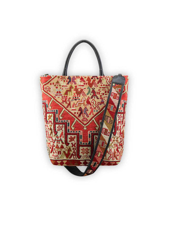 The Artemis Design Co. Sumak Kilim Tote is a stylish and versatile accessory crafted with a blend of sumptuous brown leather and vibrant, eye-catching colors. The tote features a traditional Sumak Kilim pattern in a spectrum of hues including red, white, blue, green, peach, orange, and yellow. This eclectic color combination lends a dynamic and playful aesthetic to the bag, making it a statement piece for any outfit or occasion.  (Front View)