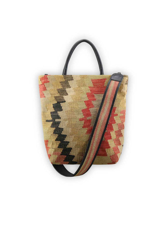 The Artemis Design Co. Sumak Kilim Tote exudes timeless sophistication with a modern twist. Crafted from premium black leather, this tote showcases a stunning Sumak Kilim pattern in a refined palette of red, khaki, black, and beige. The classic combination of colors adds a touch of understated elegance to the bag, making it a versatile accessory for any outfit. (Front View)