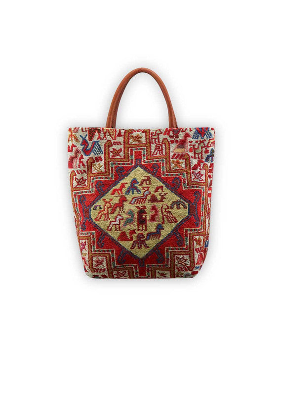The Artemis Design Co. Sumak Kilim Tote is a stylish and versatile accessory crafted with a blend of sumptuous brown leather and vibrant, eye-catching colors. The tote features a traditional Sumak Kilim pattern in a spectrum of hues including red, white, blue, green, peach, orange, and yellow. This eclectic color combination lends a dynamic and playful aesthetic to the bag, making it a statement piece for any outfit or occasion.  (Front View)