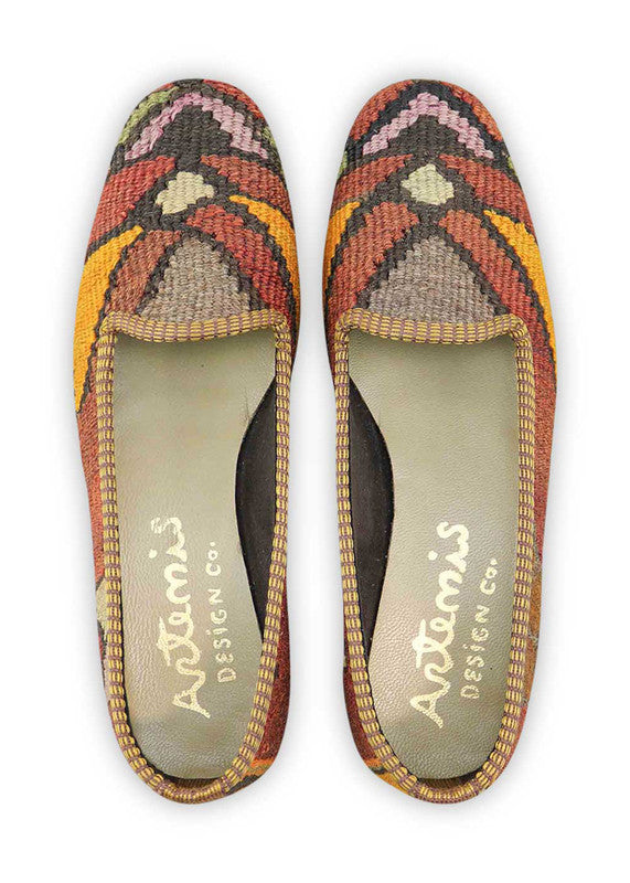 Artemis Design & Co Women's Loafers captivate with a warm and earthy color palette, featuring hues of rust, mustard, orange, white, green, black, brown, and grey. These meticulously crafted loafers seamlessly blend rich, natural tones, offering a versatile and stylish footwear option for any wardrobe. (Front View)